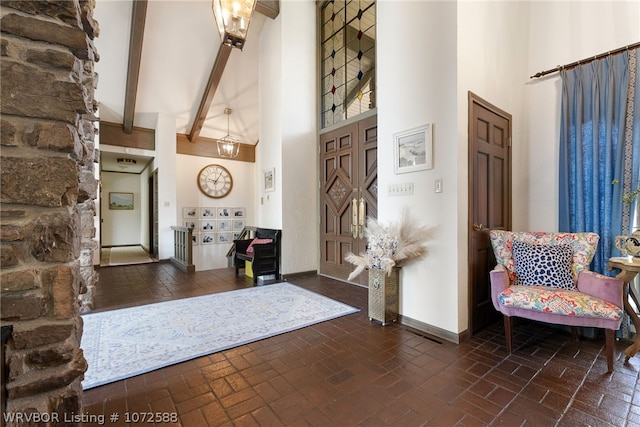 foyer entrance with beamed ceiling, high vaulted ceiling, and a chandelier