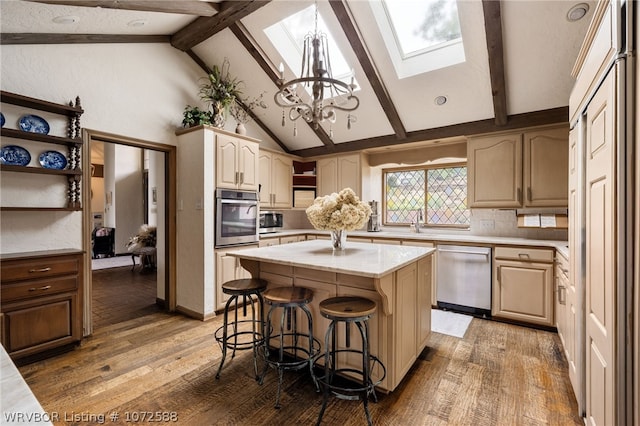 kitchen featuring stainless steel appliances, a kitchen breakfast bar, decorative backsplash, vaulted ceiling with skylight, and a kitchen island