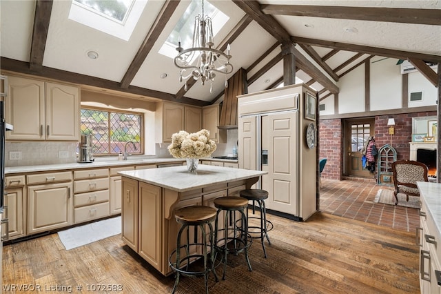 kitchen with backsplash, an inviting chandelier, a skylight, hardwood / wood-style flooring, and a kitchen island