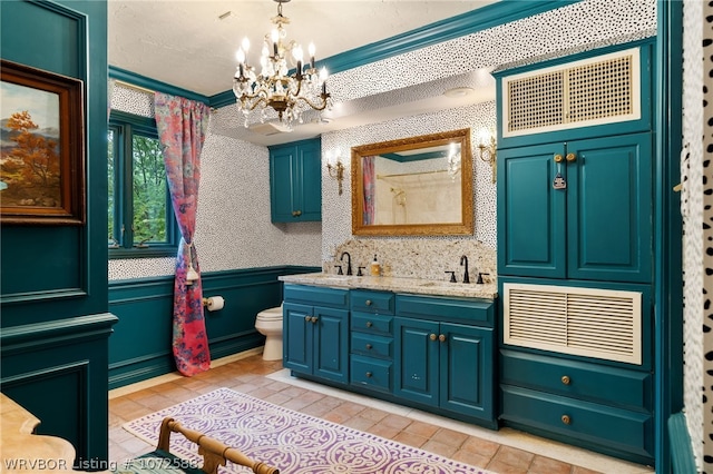 bathroom featuring tile patterned flooring, a chandelier, toilet, vanity, and ornamental molding