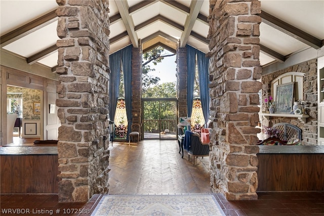 foyer with parquet floors, a fireplace, high vaulted ceiling, and ornate columns