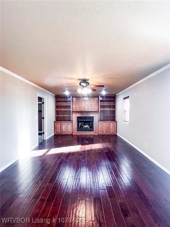 unfurnished living room with a textured ceiling, dark hardwood / wood-style floors, built in features, and crown molding