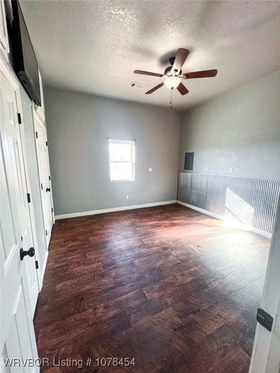 unfurnished bedroom with dark wood-type flooring, ceiling fan, and a textured ceiling