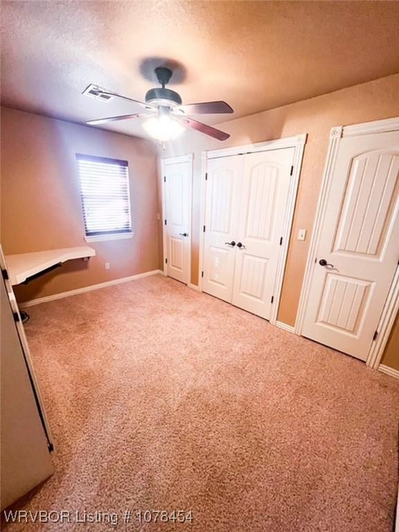 unfurnished bedroom featuring ceiling fan, a textured ceiling, and carpet flooring