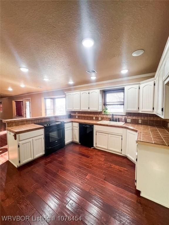 kitchen featuring kitchen peninsula, decorative backsplash, dark hardwood / wood-style floors, black appliances, and sink