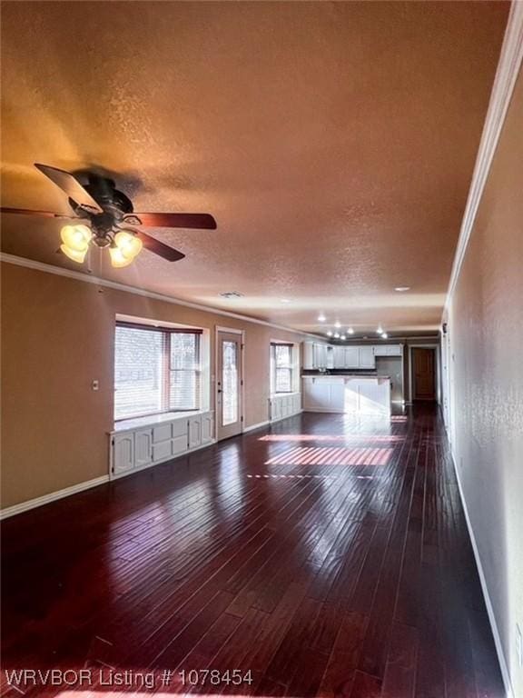 unfurnished living room featuring ceiling fan, dark hardwood / wood-style flooring, crown molding, and a textured ceiling