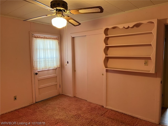 doorway featuring carpet, ceiling fan, and ornamental molding