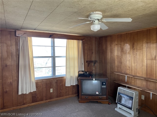 miscellaneous room featuring carpet flooring, heating unit, wooden walls, and ceiling fan