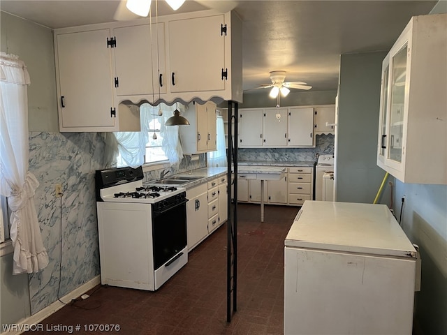 kitchen with washer / dryer, ceiling fan, white cabinets, and white gas range oven