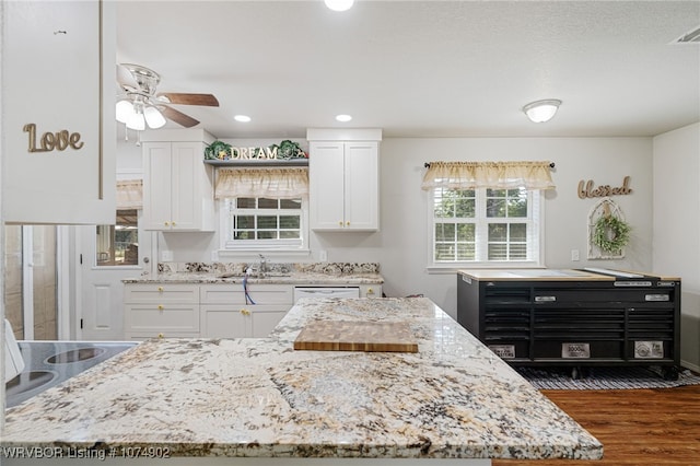 kitchen with light stone countertops, white cabinetry, and sink