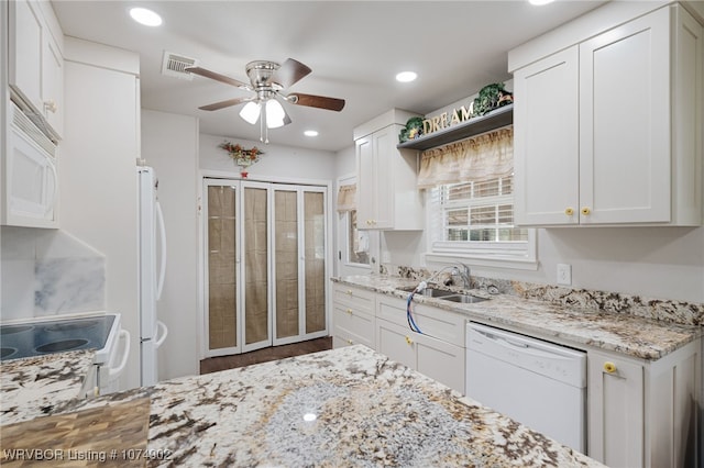 kitchen with white cabinetry, light stone counters, white appliances, and sink