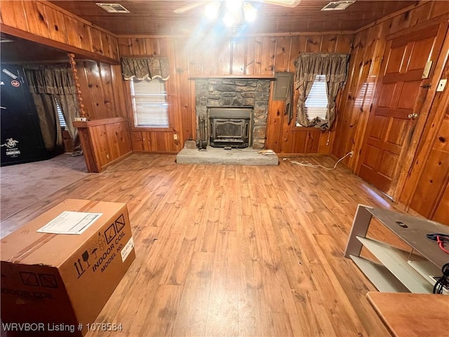 unfurnished living room with light hardwood / wood-style flooring, wooden ceiling, ceiling fan, and wood walls