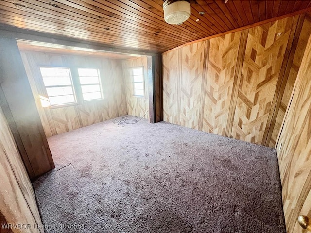 carpeted spare room featuring wood ceiling and wooden walls