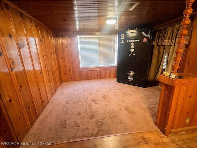 carpeted spare room featuring wooden walls and wooden ceiling