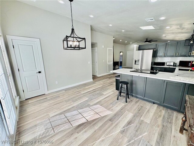 kitchen featuring ceiling fan with notable chandelier, black appliances, light hardwood / wood-style floors, hanging light fixtures, and lofted ceiling