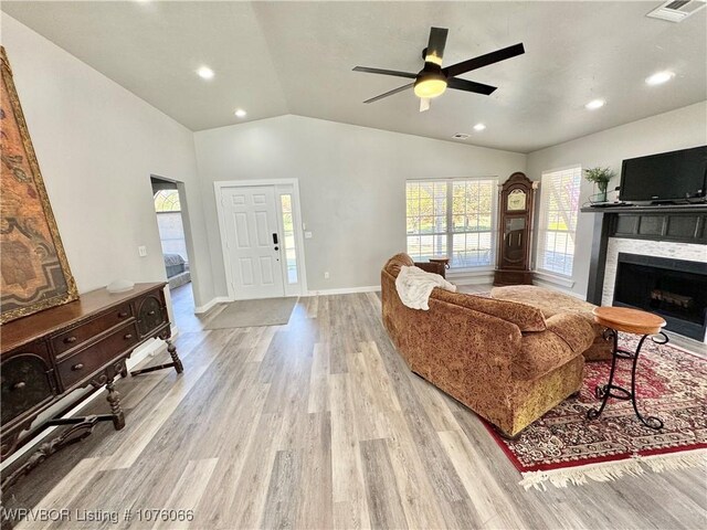 living room with ceiling fan, light wood-type flooring, and vaulted ceiling