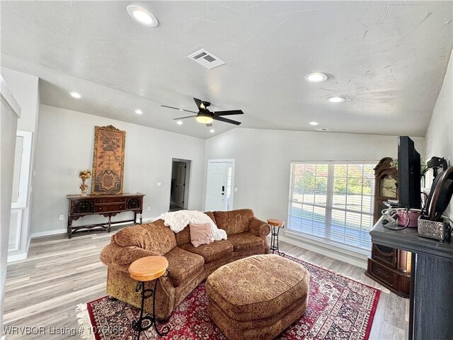 living room featuring ceiling fan, light wood-type flooring, and vaulted ceiling