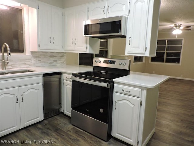 kitchen featuring sink, kitchen peninsula, dark hardwood / wood-style floors, white cabinetry, and stainless steel appliances