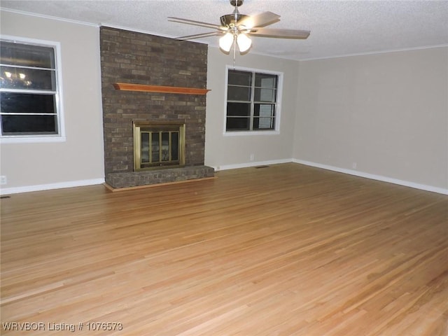 unfurnished living room featuring a fireplace, a textured ceiling, light hardwood / wood-style flooring, and ceiling fan