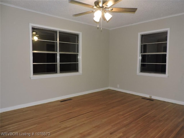 empty room with wood-type flooring, a textured ceiling, and ornamental molding