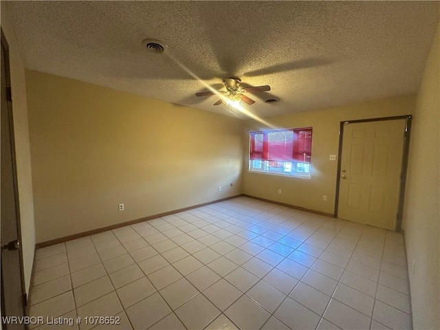 tiled empty room with ceiling fan and a textured ceiling