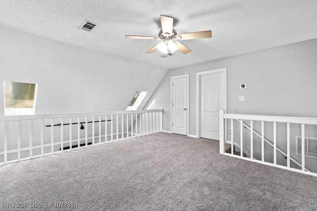 bonus room with carpet, ceiling fan, lofted ceiling with skylight, and a textured ceiling