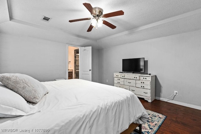 bedroom with ceiling fan, dark hardwood / wood-style floors, a raised ceiling, and ensuite bathroom