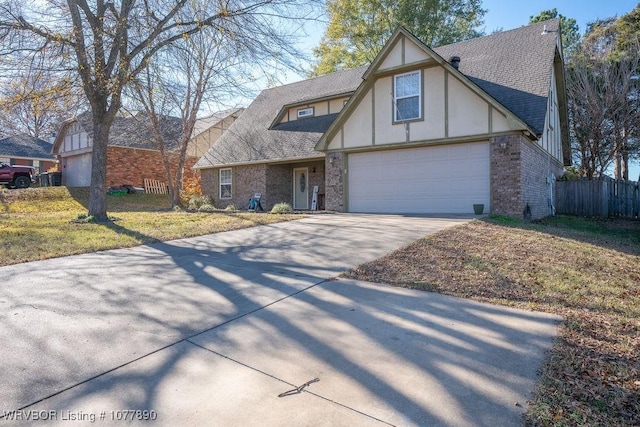 tudor home featuring a garage and a front lawn