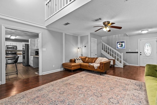 living room featuring ceiling fan, dark wood-type flooring, and a textured ceiling