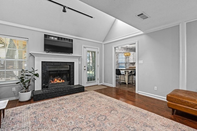 living room with a fireplace, wood-type flooring, lofted ceiling, and ornamental molding