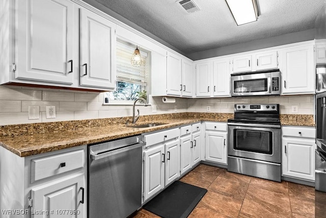 kitchen featuring appliances with stainless steel finishes, a textured ceiling, white cabinetry, and sink