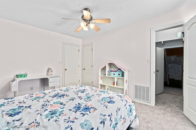 carpeted bedroom with ceiling fan and a textured ceiling