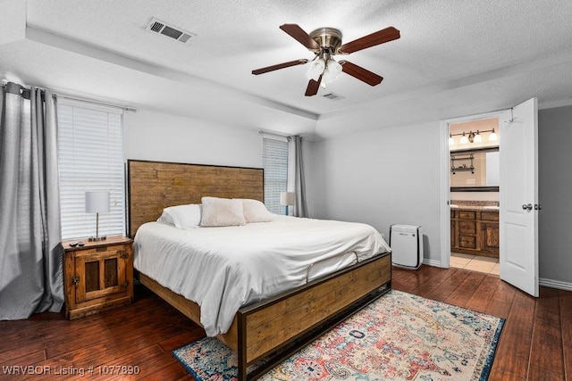 bedroom featuring a textured ceiling, dark hardwood / wood-style flooring, ensuite bathroom, and ceiling fan