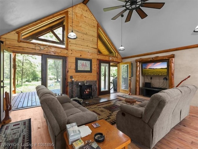 161129 N 4550th Rd, Talihina, OK 74571 - living room featuring a wood stove, wood finished floors, ceiling fan, wood walls, and high vaulted ceiling