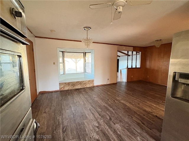 unfurnished living room featuring dark wood-type flooring, ceiling fan with notable chandelier, and ornamental molding