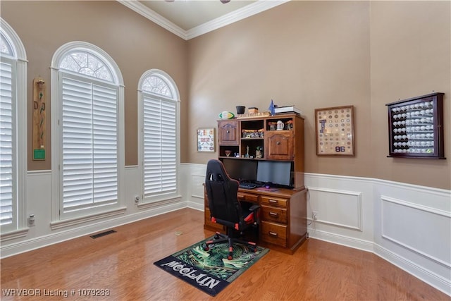 office with ornamental molding, wainscoting, visible vents, and wood finished floors