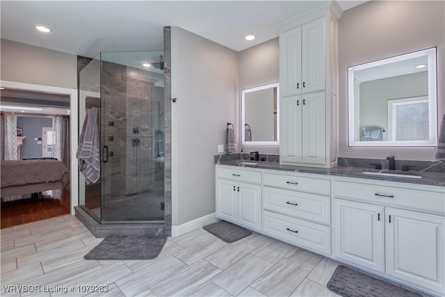 full bath with a stall shower, a sink, baseboards, and double vanity