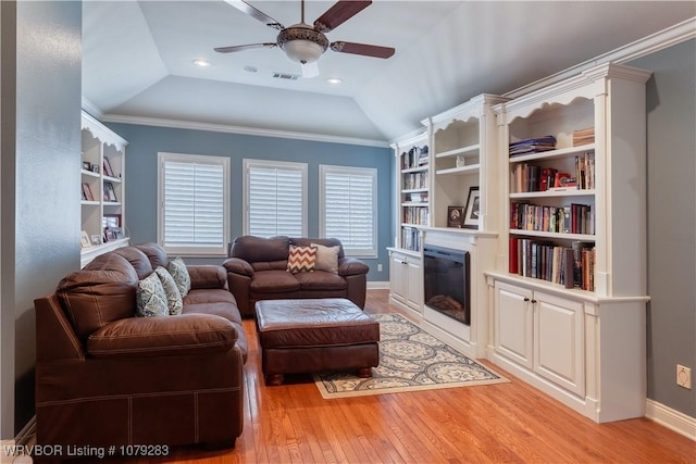 living room featuring ceiling fan, visible vents, vaulted ceiling, light wood-type flooring, and a glass covered fireplace