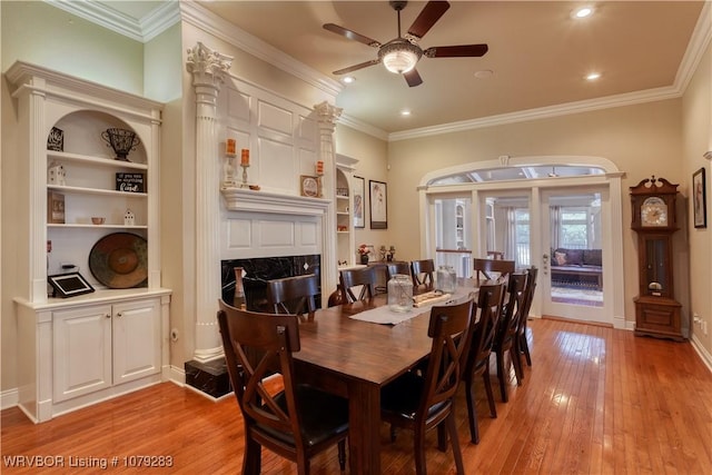 dining area featuring baseboards, built in features, ornamental molding, light wood-type flooring, and a fireplace