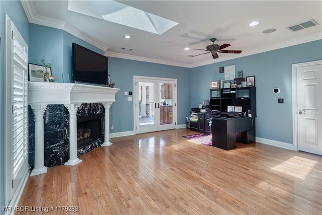 office featuring baseboards, visible vents, crown molding, light wood-style floors, and a high end fireplace