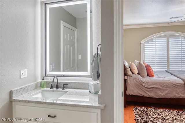 bathroom with visible vents, vanity, ornamental molding, and a textured wall