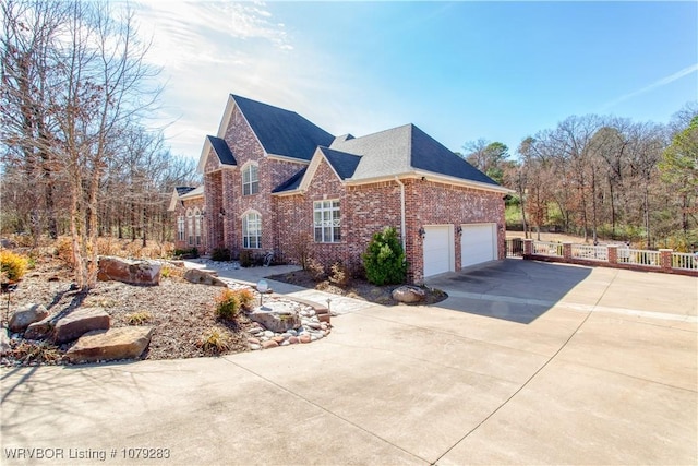 view of property exterior featuring a garage, a shingled roof, concrete driveway, fence, and brick siding