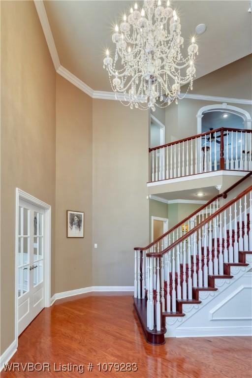 stairway with a high ceiling, baseboards, crown molding, and wood finished floors