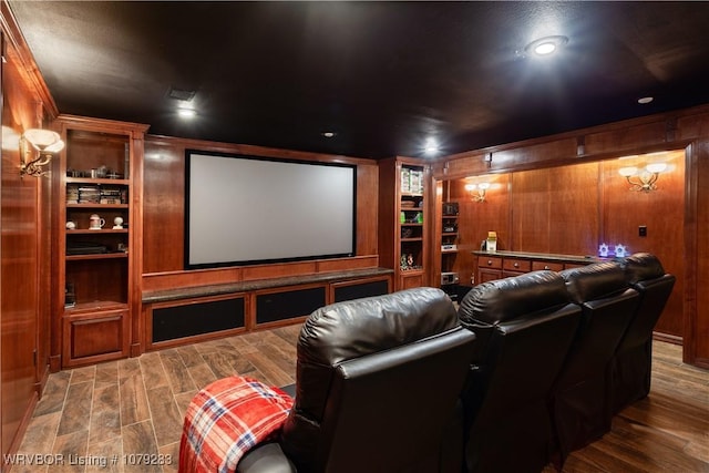 home theater featuring built in shelves, wood walls, and wood finished floors