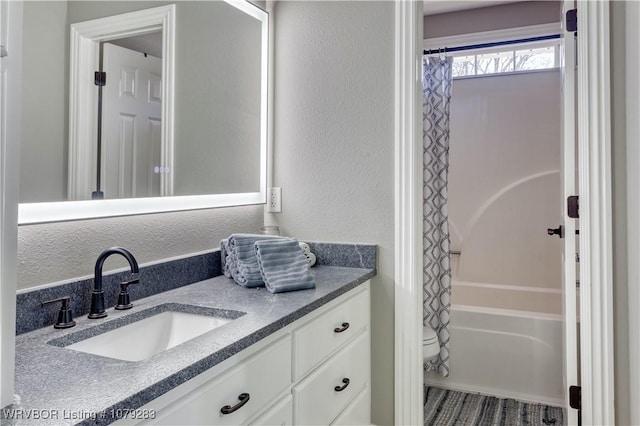 bathroom featuring a textured wall, vanity, toilet, and shower / bath combo with shower curtain