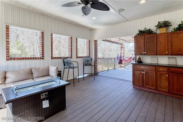 wooden terrace with a ceiling fan and an outdoor living space with a fire pit