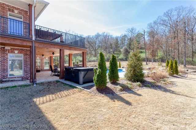 view of yard featuring a balcony, a hot tub, ceiling fan, and a patio