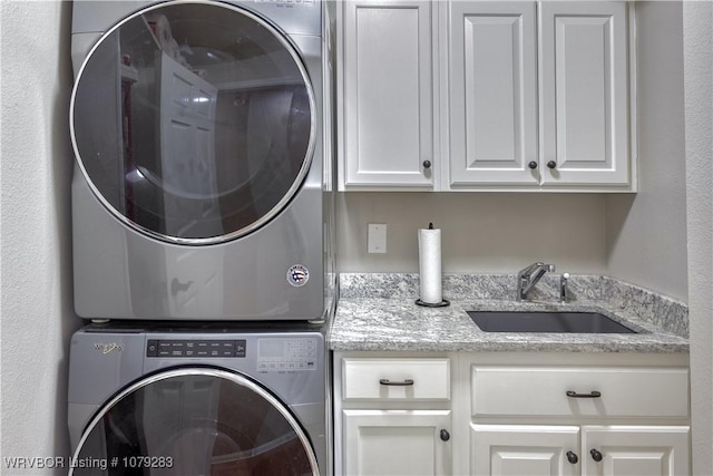 laundry room with cabinet space, a sink, and stacked washer and clothes dryer