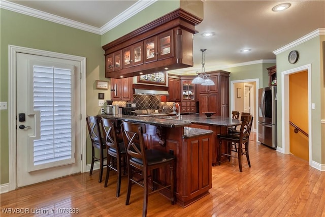 bar featuring crown molding, tasteful backsplash, light wood-style flooring, smart refrigerator, and exhaust hood