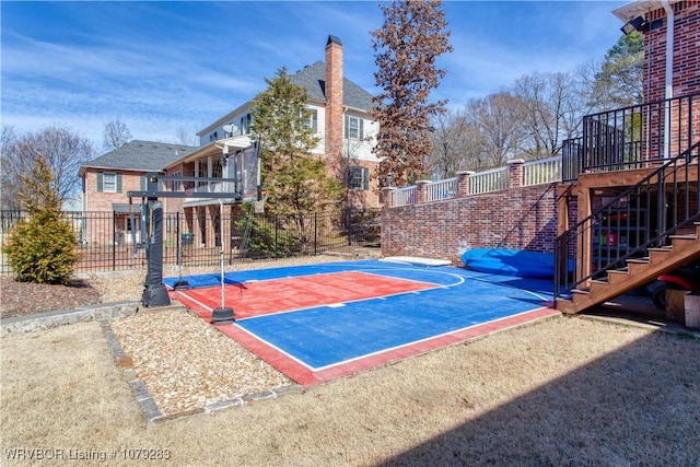 view of basketball court with stairs, basketball hoop, and fence